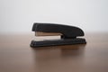 Black stapler lying on brown wood table