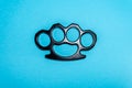 Black Steel brass knuckles blue background hooligan fight, fighting without rules, street banditry, injuries