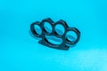 Black Steel brass knuckles blue background hooligan fight, fighting without rules, street banditry, injuries