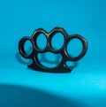 Black Steel brass knuckles blue background hooligan fight, fighting without rules, street banditry, injuries