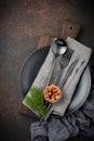 Black steel cutlery set fork, knife, spoon on gray linen napkin, black ceramic plate and festive decoration.Selective focus. Royalty Free Stock Photo