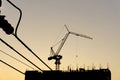 A Black steel tower crane standing on the top of a black building on construction, high voltage electricity cables line on the Royalty Free Stock Photo