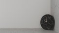 Black stone clock, copper needle leaning on the corner between the floor and the white wall. Smooth and rough surface