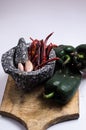 Black stone mortar with ingredients for sauce, red chili peppers, raw garlic cloves. Royalty Free Stock Photo