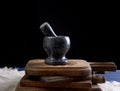 Black stone mortar with pestle for grinding spices and herbs on a brown wooden board Royalty Free Stock Photo