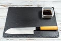 Black stone plate board on a white rusty background with a Sushi and Sashimi Knive on it