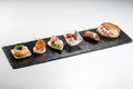 Black stone rectangular tray with shrimp tartare snack cannoli swordfish ravioli with robbiola tartina nordica mousse aubergine Royalty Free Stock Photo