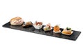 Black stone rectangular tray with shrimp tartare snack cannoli swordfish ravioli with robbiola tartina nordica mousse aubergine Royalty Free Stock Photo