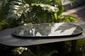 Black stone table with glass on it green plants in the background. Natural composition