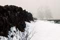 Black stone wall with a pile of snow next to it in a rural area in winter on a gloomy day Royalty Free Stock Photo