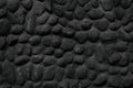 Black stone wall texture of painted natural large pebbles