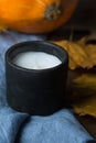 Black Stone White Candle Orange Pumpkin Dry Colorful Autumn Leaves on Blue Linen Cloth. Cozy Contemplative Atmosphere.Thanksgiving