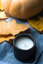 Black Stone White Candle Orange Pumpkin Dry Colorful Autumn Leaves on Blue Linen Cloth. Cozy Contemplative Atmosphere.Thanksgiving