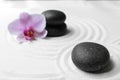 Black stones and flower on sand with pattern. Zen, meditation, harmony Royalty Free Stock Photo