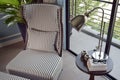 Black striped easy chair in the corner with decorative brass lamp