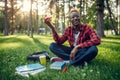 Black student with apple sitting on the grass