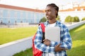 Black student guy hugs laptop standing with backpack near university Royalty Free Stock Photo