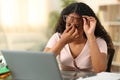 Black student suffering eyestrain studying at home