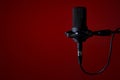 Black studio condenser microphone on red background,