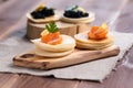 Black sturgeon caviar and pieces of salmon on pancakes on a wooden plate close-up Royalty Free Stock Photo