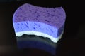 On a black stylish glossy background is a female purple sponge for a body of purple and white with reflection