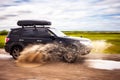 Black Subaru Forester driving on a dirt road with puddles. Water splashes from under the wheels