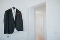 Black suit and a shirt is hanging from a hanger on a door