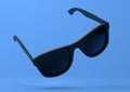 Black summer sunglasses falling down on a pastel bright blue background Royalty Free Stock Photo