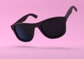 Black summer sunglasses falling down on a pastel bright pink background Royalty Free Stock Photo