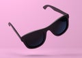 Black summer sunglasses falling down on a pastel bright pink background Royalty Free Stock Photo