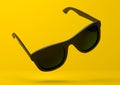 Black summer sunglasses falling down on a pastel bright yellow background Royalty Free Stock Photo