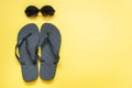 Black sun glasses and beach flip flops on yellow. Summer tropical vacations Royalty Free Stock Photo