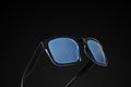 Black sunglasses with blue tinted frames on dark background