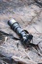 Black super telephoto lens and digital camera body on old log and ancient stone