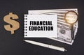 On a black surface are dollars, a pen and a notepad with the inscription - FINANCIAL EDUCATION Royalty Free Stock Photo