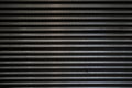 Black surface of a latticed metal fence with jagged stripe elements