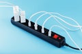 Black surge protector with a red button and connected white wires of electrical appliances on a blue background. Royalty Free Stock Photo