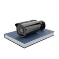 A black surveillance camera rests on a closed blue book isolated on white background Royalty Free Stock Photo