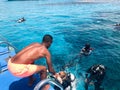 A black, swarthy, Arab athletic athletic man helping divers in black scuba diving suits with oxygen bottles sinks under the transp