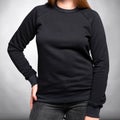 Black sweatshirt jacket with sleeves dressed on a girl on a gray background. Vertical orientation