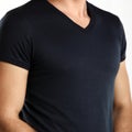 Black t-shirt template of man waring blank classic shirt. Torso of a slender adult man in a black t-shirt. copyspace