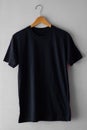 Black t-shirt on wood hanger isolated on grey grunge background