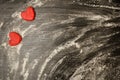 Black table with scattered flour, red dough hearts in the corner, space for text. Top view