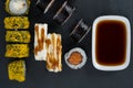 On a black table, top view, assorted Japanese salmon rolls with teriyaki and baked in tempura and soy sauce in a container Royalty Free Stock Photo