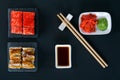 On a black table, top view, rolls with eel, teriyaki sauce, sesame seeds, flying fish caviar, wooden sticks and seasonings, soy Royalty Free Stock Photo