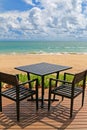 Black table for two on wooden balcony with blurred beach and blu