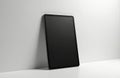 Black tablet mockup leans on light wall. Blank screen faces viewer for graphic design presentation. Tablet modern device lies on Royalty Free Stock Photo