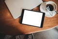 A black tablet pc with blank desktop white screen with laptop and coffee cup on wooden table Royalty Free Stock Photo