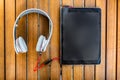 Black tablet PC and white headphones on the wooden background Royalty Free Stock Photo