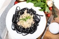 Black tagliatelle pasta made with cuttlefish ink with parmesan cheese and ham sauce Royalty Free Stock Photo